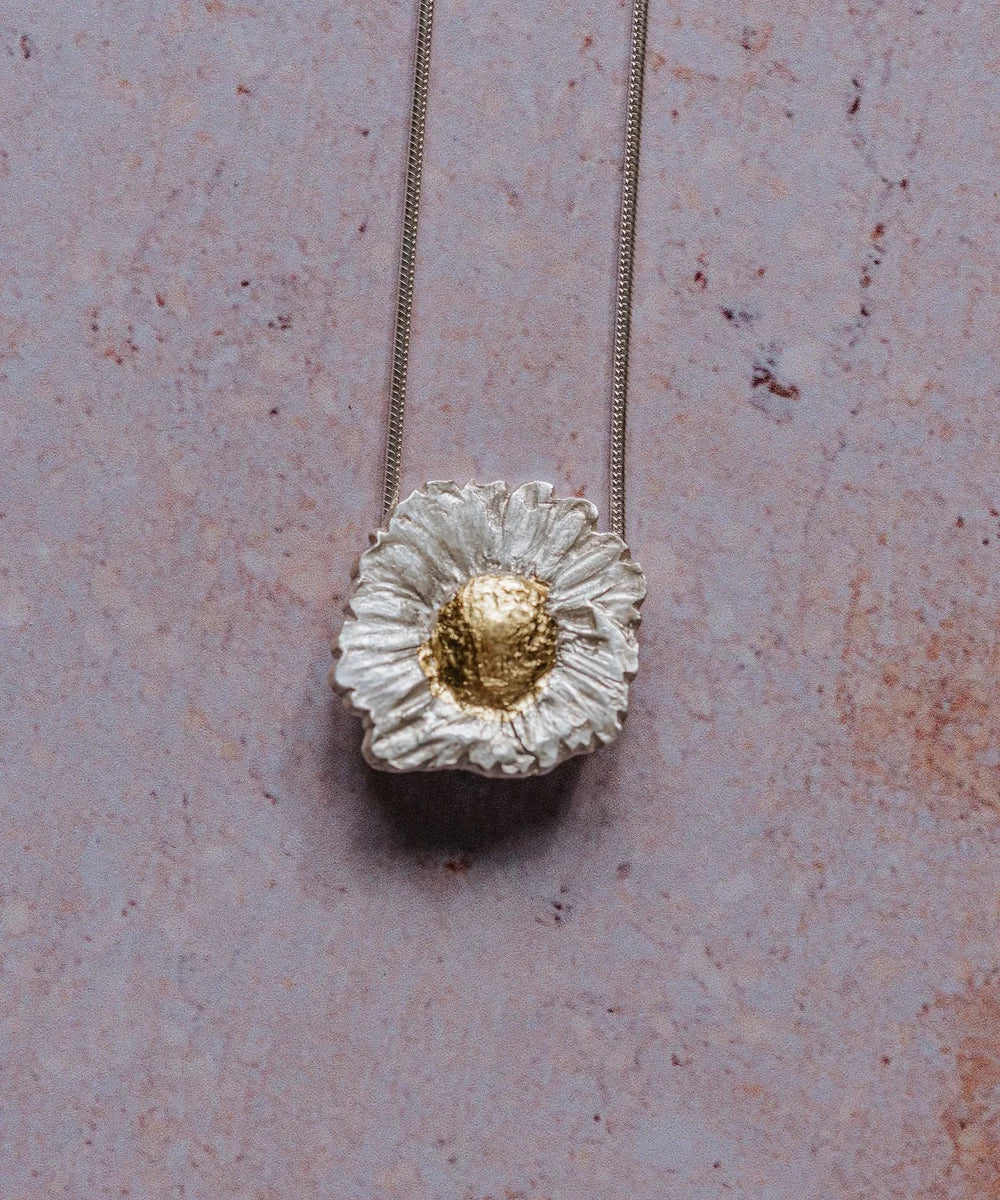 close-up of silver daisy pendant necklace with gold-leaf centre on sterling silver chain