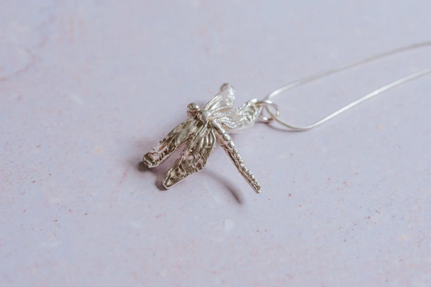 Artisan silver dragonfly necklace shown from side angle with intricate wing detail on sterling silver chain