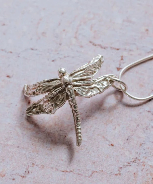 Close-up handmade silver dragonfly pendant necklace with detailed textured wings symbolising transformation and renewal