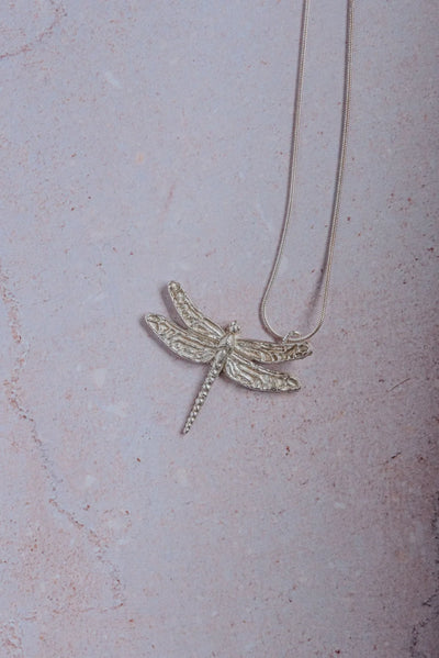 Handmade silver dragonfly necklace with detailed textured wings on sterling snake chain