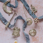 Flat lay of unique handmade silver jewellery including dragon pendant with citrine, crescent moon necklace, broomstick pendant, and whimsical designs from The Magic of Fireflies and Dragonflies