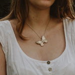 Large recycled silver butterfly pendant on snake chain, worn by model in white dress