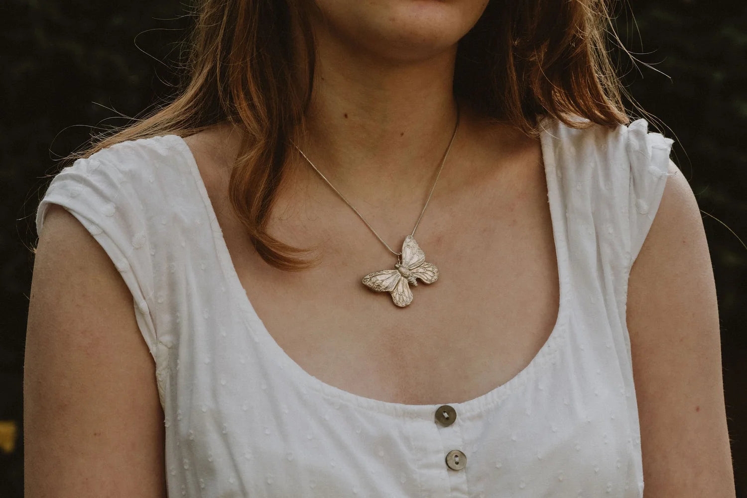 Large recycled silver butterfly pendant on snake chain, worn by model in white dress