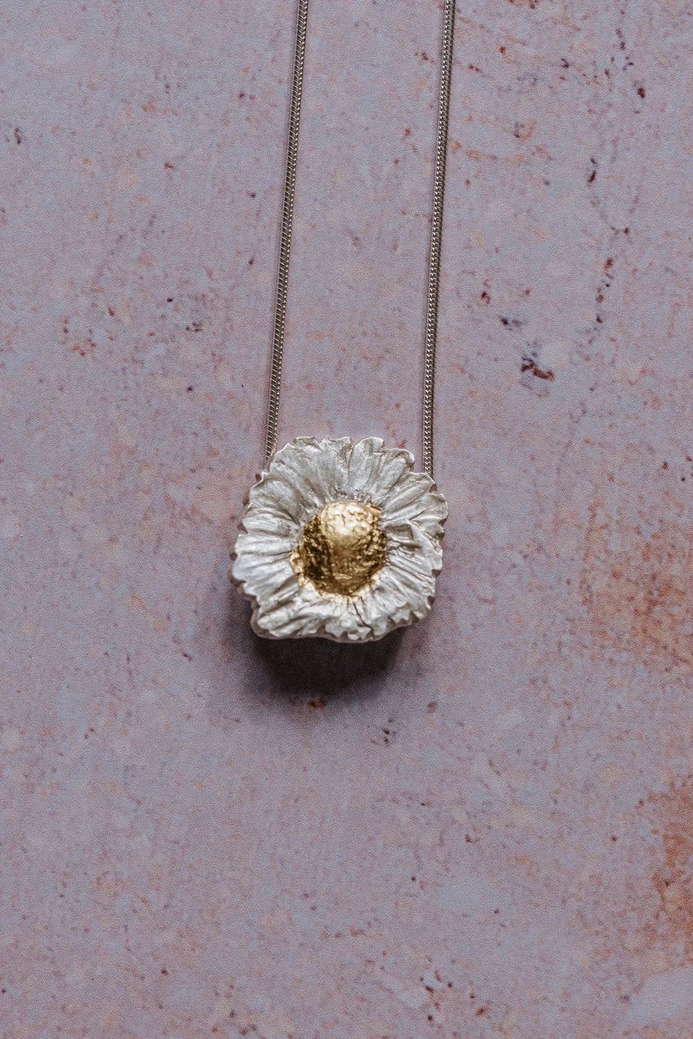 close-up of silver daisy pendant necklace with gold-leaf centre on sterling silver chain