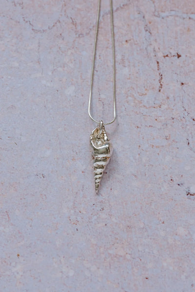 Handmade recycled silver mollusc shell pendant on 16-inch chain, displayed on textured stone background
