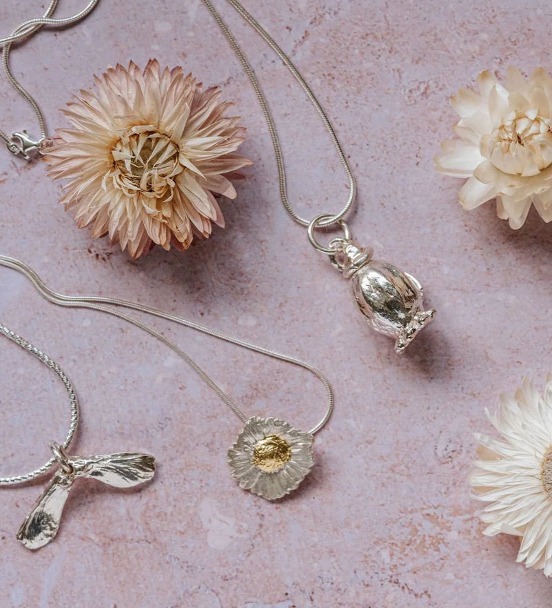 Poppy seedhead silver pendant necklace styled with other botanical silver jewellery and dried flowers