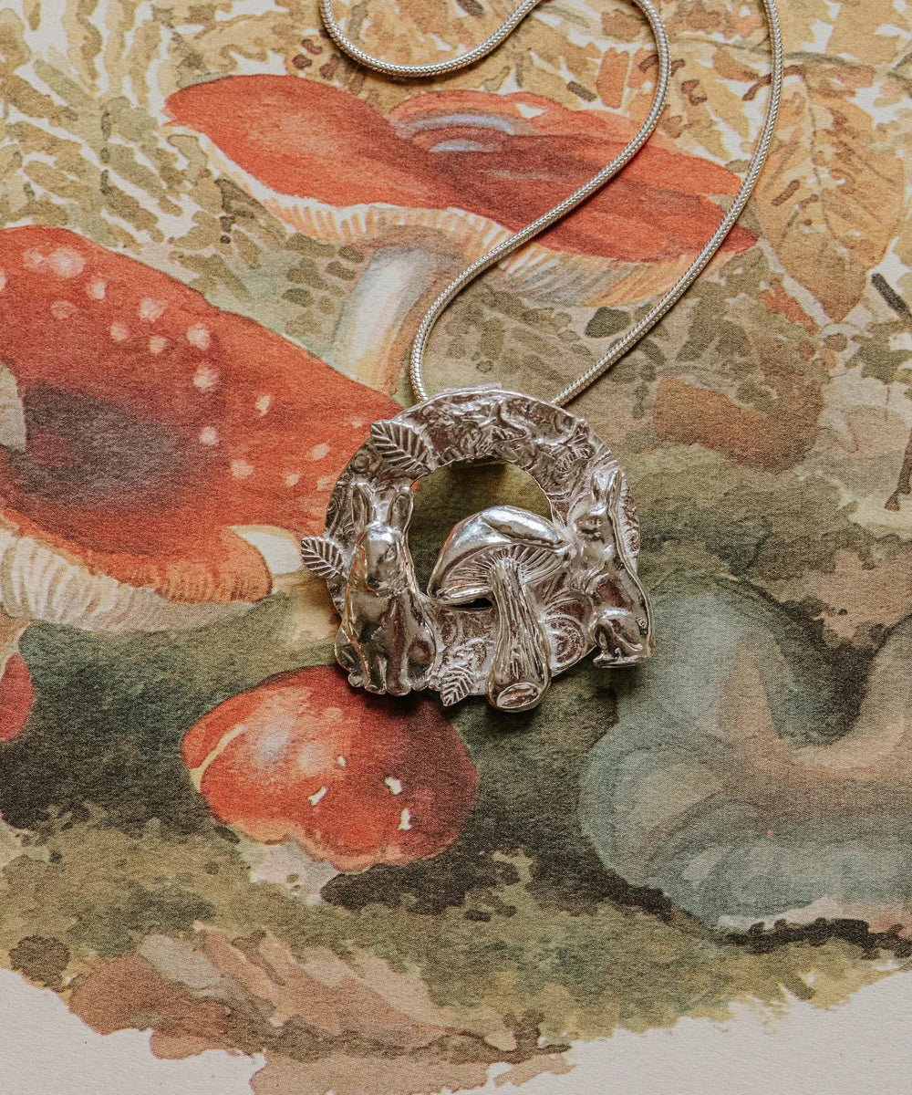 Silver rabbit and toadstool pendant necklace styled on a vintage mushroom illustration featuring red and green toadstools