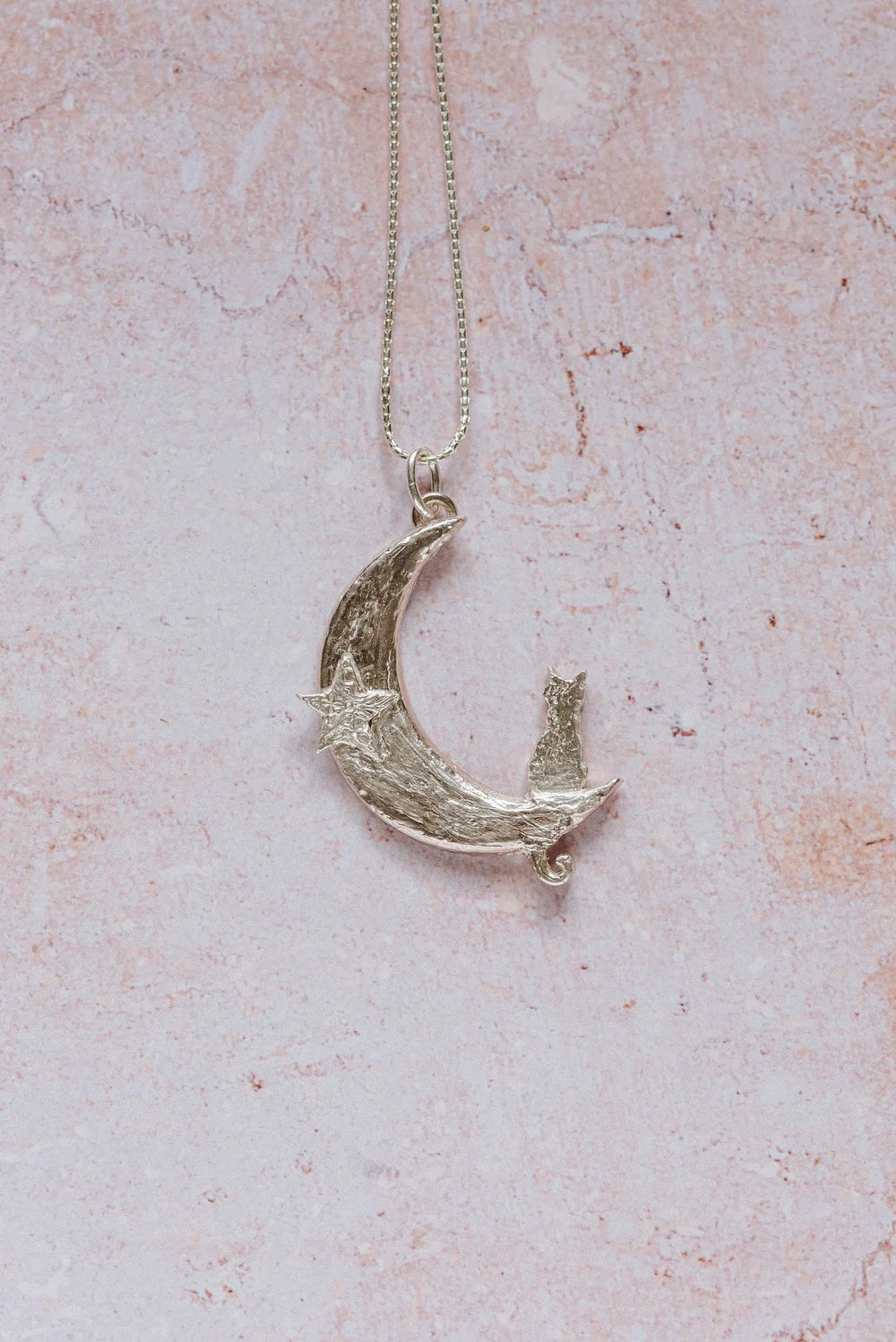 Close-up of handmade silver cat and crescent moon pendant necklace with star detail