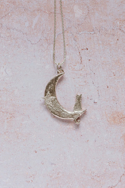 Close-up of handmade silver cat and crescent moon pendant necklace with star detail