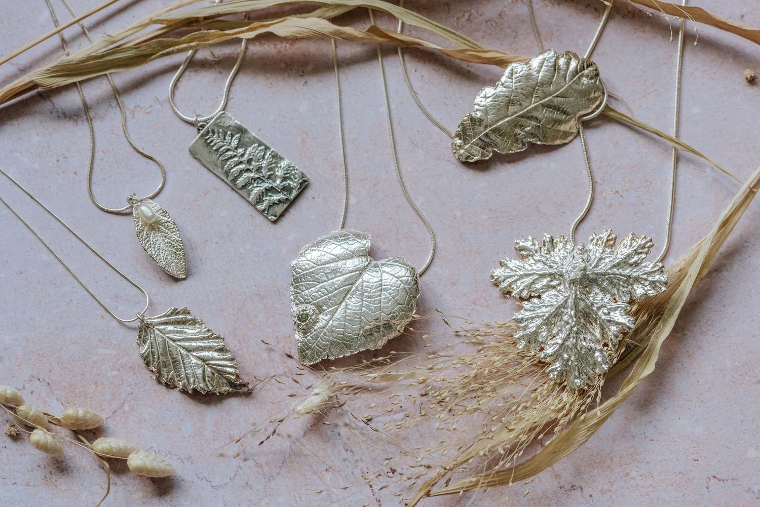 Collection of handmade silver clay leaf pendant necklaces inspired by nature, featuring heart leaf, oak leaf and fern designs on chains