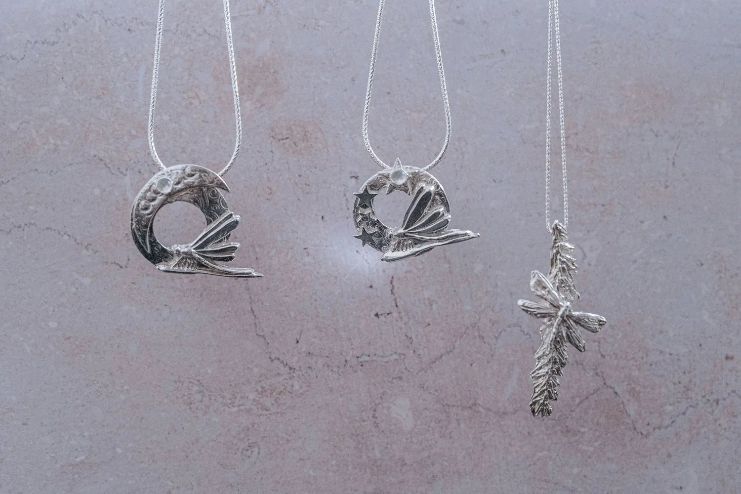 Three handmade silver dragonfly pendants on sterling chains, including moon dragonfly pendant, star dragonfly pendant, and catkin dragonfly pendant, artisan nature inspired jewellery gifts UK