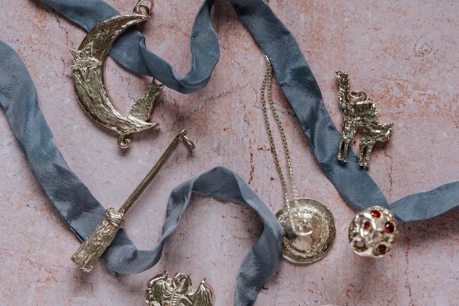 Silver unique witchy jewellery pieces with ribbons on a textured surface