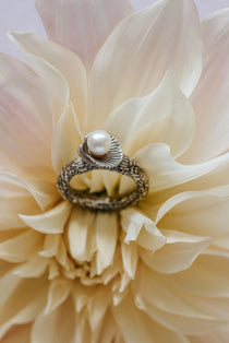 Handmade recycled silver ring with freshwater pearl in shell setting, displayed on cream dahlia flower