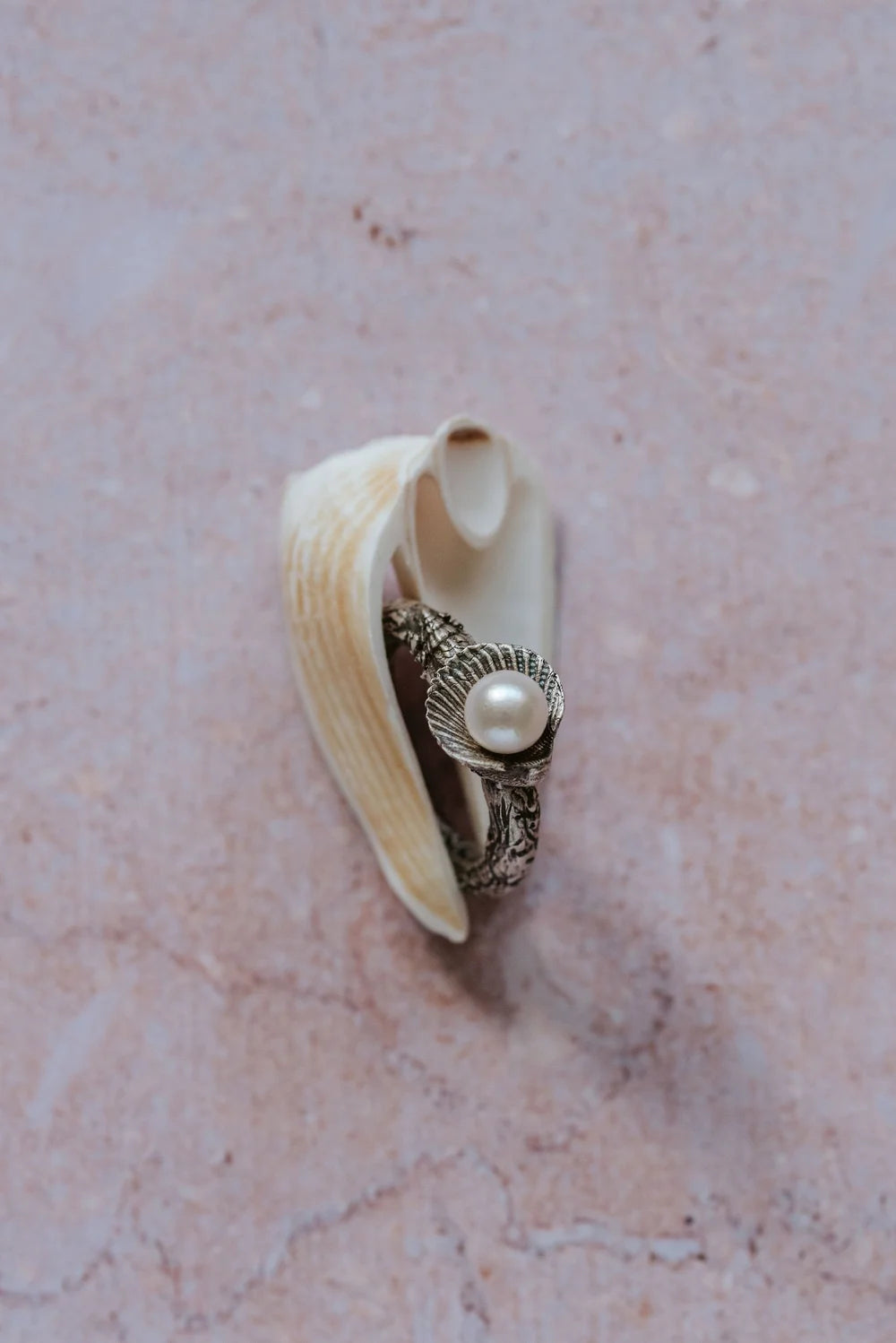 Handmade recycled silver ring with freshwater pearl in shell setting, displayed on natural seashell
