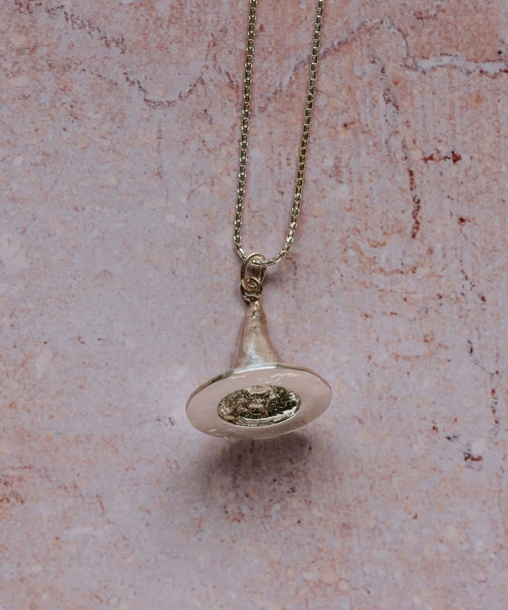 Close-up of handmade silver witch’s hat pendant necklace on 16-inch sterling silver chain, displayed against pink textured background