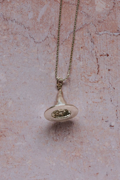 Close-up of handmade silver witch’s hat pendant necklace on 16-inch sterling silver chain, displayed against pink textured background